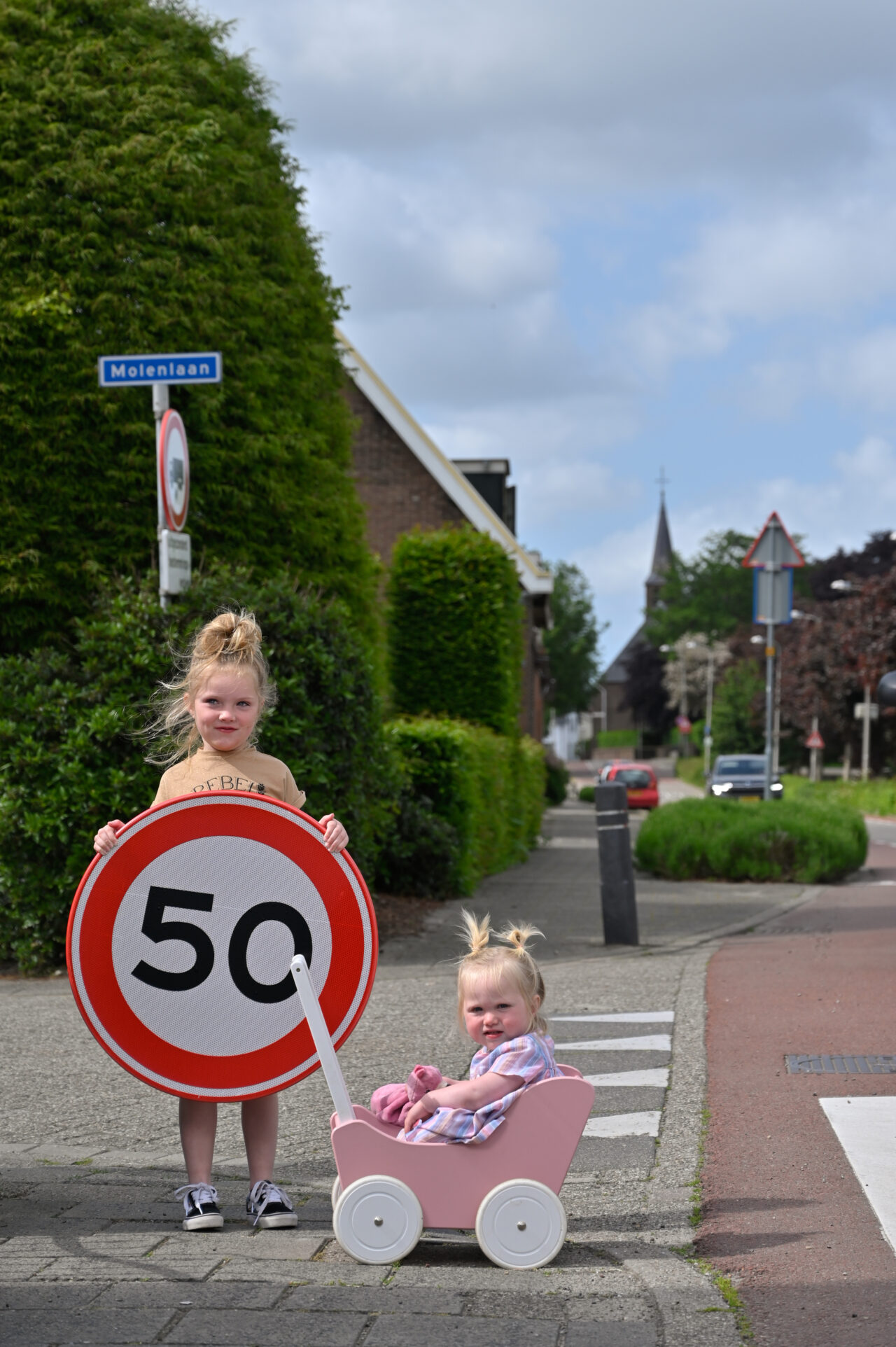 Twee kinderen op straat met een snelheidsbord (50 km) in hun handen voor de snelheidscampagne voor de gemeente Nieuwkoop